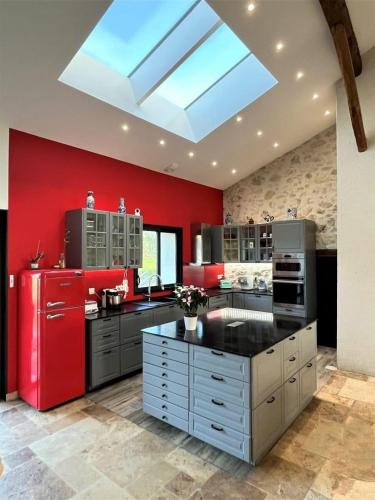 une grande cuisine avec des murs rouges et une lucarne dans l'établissement les 3 sapins de guillemet, à Saint-Pierre-de-Bat