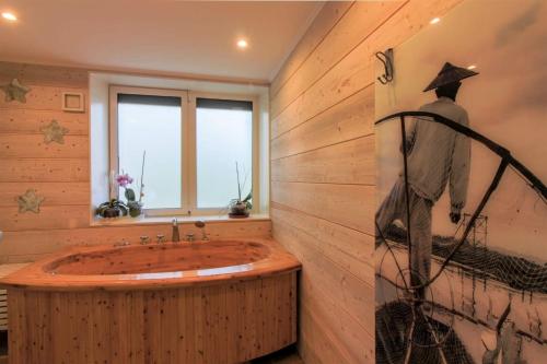 La salle de bains est pourvue d'une baignoire et d'une peinture murale. dans l'établissement les 3 sapins de guillemet, à Saint-Pierre-de-Bat