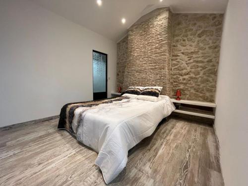 une chambre avec un grand lit et un mur de briques dans l'établissement les 3 sapins de guillemet, à Saint-Pierre-de-Bat
