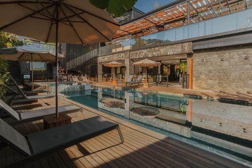 a pool with chairs and umbrellas next to a building at Pousada Boutique Villa Valley in Praia do Rosa