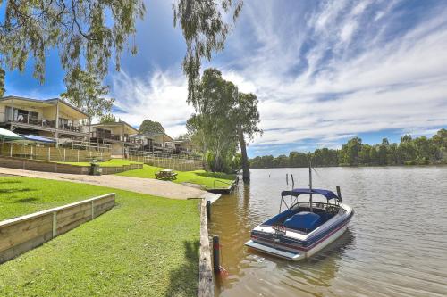 a boat is docked on a river with houses at Rivergardens Holiday Park Mildura in Gol Gol
