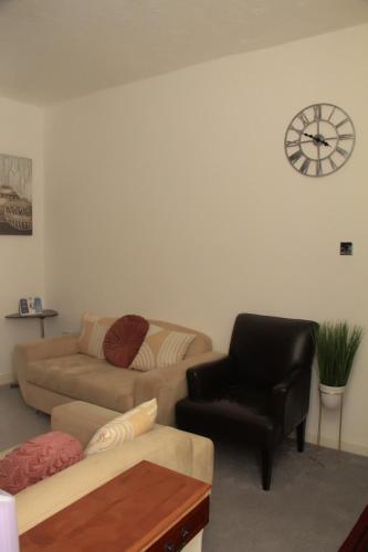 a living room with a couch and a chair and a clock at Spacious House, Near Haigh Woodland Park, Wifi, Parking in Leigh