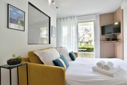 Un dormitorio con una cama blanca y un sofá amarillo. en Escapade - Appartement avec jardin et parking, en Dinan