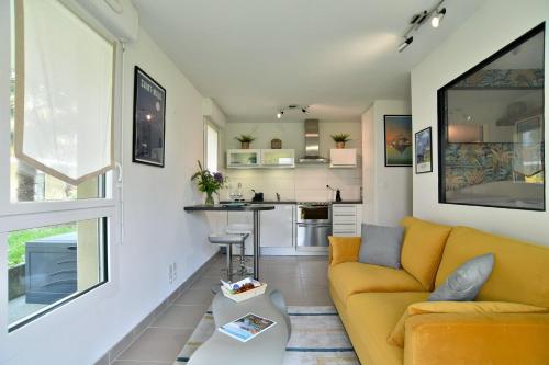 Una sala de estar con un sofá amarillo y una cocina. en Escapade - Appartement avec jardin et parking, en Dinan