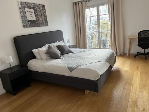 une chambre avec un lit et une grande fenêtre dans l'établissement Appartement Quartier Grande Armée Paris 100 m2, à Paris