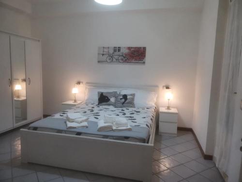 a white bedroom with a large bed with two lamps at The Happy Place Montecatini in Montecatini Terme