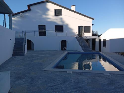 a swimming pool in front of a white house at Casa da Avó Bia in Penhascoso