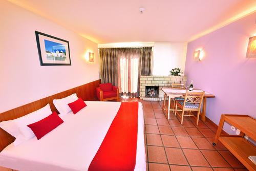 a bedroom with a bed and a table and a fireplace at Hotel Apartamento Porto Covo in Porto Covo