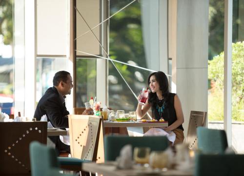 a man and woman sitting at a table in a restaurant at Novotel Makassar Grand Shayla in Makassar