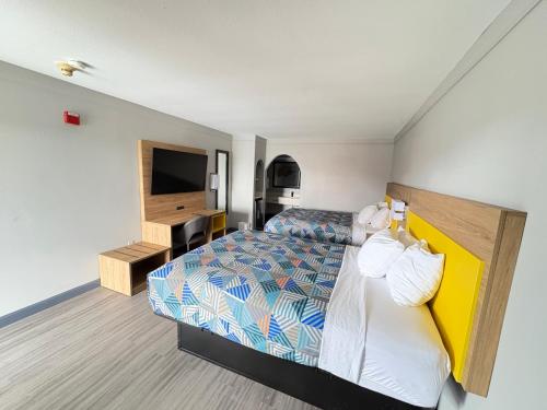 a hotel room with a bed and a television at Days Inn by Wyndham Gonzales in Gonzales