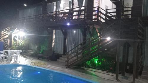 a building with a staircase next to a swimming pool at night at Villas de Portugal - Apartamento com suíte e Varanda Gourmet, Piscina - Praia do Ervino in São Francisco do Sul