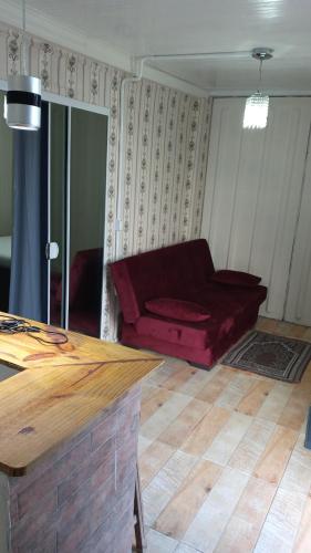 a living room with a red couch in a room at Villas de Portugal - Apartamento com suíte e Varanda Gourmet, Piscina - Praia do Ervino in São Francisco do Sul