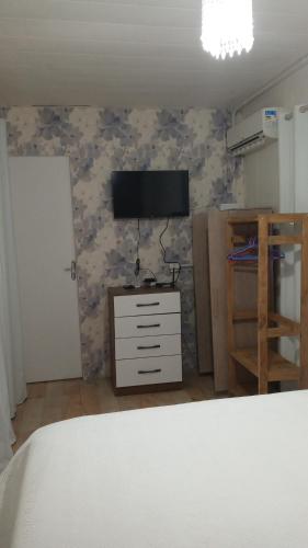 a bedroom with a tv and a dresser with a dresser at Villas de Portugal - Apartamento com suíte e Varanda Gourmet, Piscina - Praia do Ervino in São Francisco do Sul
