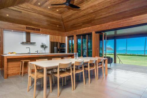 a dining room with a table and chairs and windows at Yangaro in Airlie Beach
