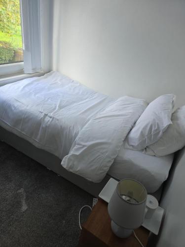a bed with white sheets and pillows next to a window at Poshval in Manchester