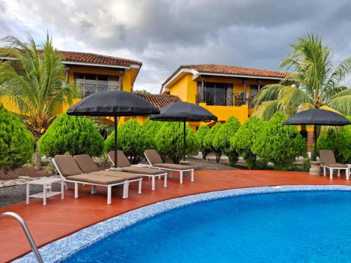 a pool with chairs and umbrellas next to a house at Hotel Jardín Garden de Granada Nicaragua in Granada