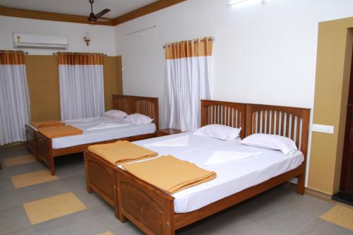 two twin beds in a room withermottermott at Pearl Beach Bungalow in Alleppey