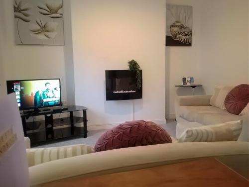 a living room with two white couches and a flat screen tv at Spacious House, Near Haigh Woodland Park, Wifi, Parking in Leigh
