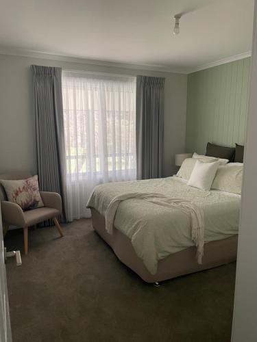 una camera da letto con un letto, una sedia e una finestra di Cottage amongst the Pines a Wamboin