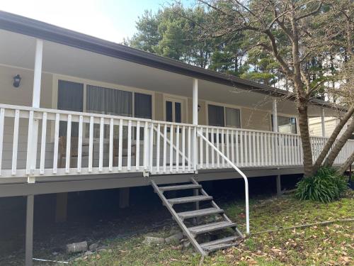 a house with a staircase in front of it at Cottage amongst the Pines in Wamboin