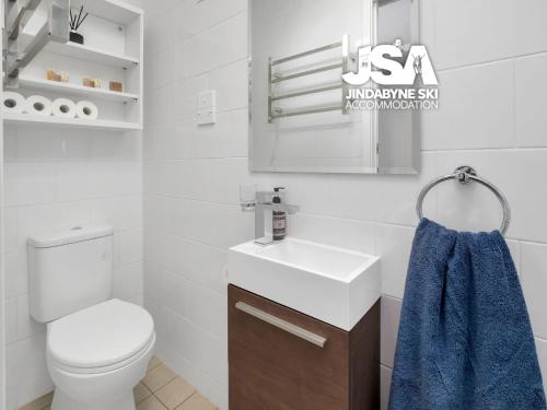 a white bathroom with a toilet and a sink at Birralee 1 in Jindabyne