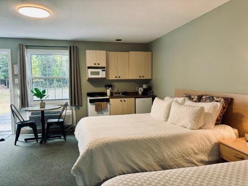 a bedroom with a bed and a table and a kitchen at Lakeside Stays in Plaster Rock