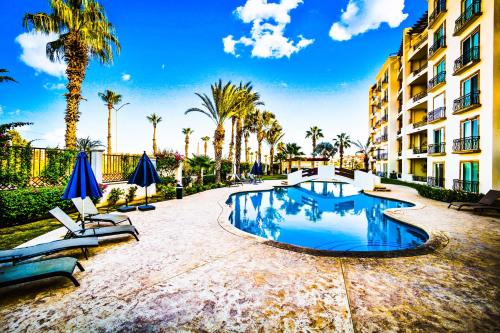 a swimming pool in front of a building with palm trees at Casa Sirena- Secure & Private Poolside Retreat in Cabo San Lucas