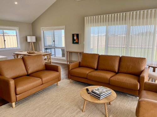 a living room with two brown couches and a table at Foxhill Shores - WIFI outside pets in Robe