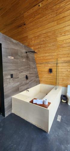 a bath tub in a room with a wooden wall at Cabañas Siete Puntas in Mazamitla