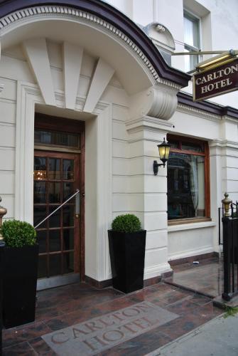 a front door of a hotel with two plants in front at Carlton Hotel in London
