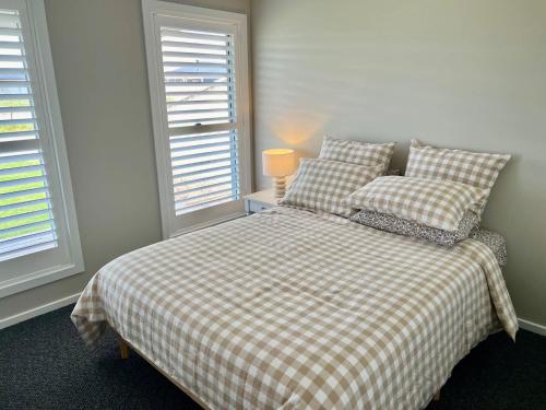 a bedroom with a bed and two windows at Foxhill Shores - WIFI outside pets in Robe