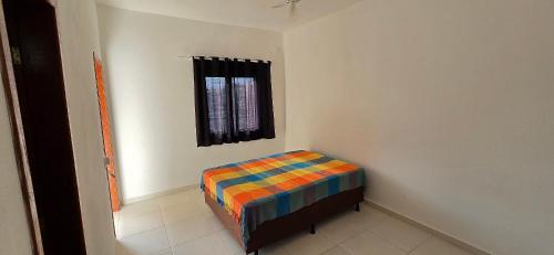 Una cama pequeña en una habitación con ventana. en Casa Temporada Lua Nova, en Guriri