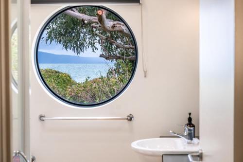 baño con espejo redondo sobre un lavabo en Southerlys Beach House, en Dolphin Sands