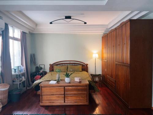 a bedroom with a bed and a wooden dresser with a table at Sunday Inn in Tainan
