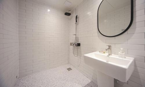 a white bathroom with a sink and a mirror at From H Lazy Heaven in Changwon
