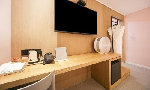 a room with a desk with a television on a wall at From H Lazy Heaven in Changwon