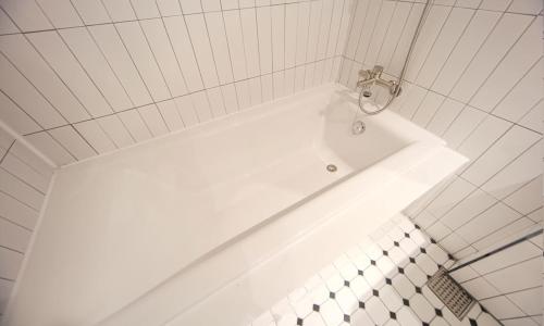 a white bath tub in a white tiled bathroom at From H Lazy Heaven in Changwon