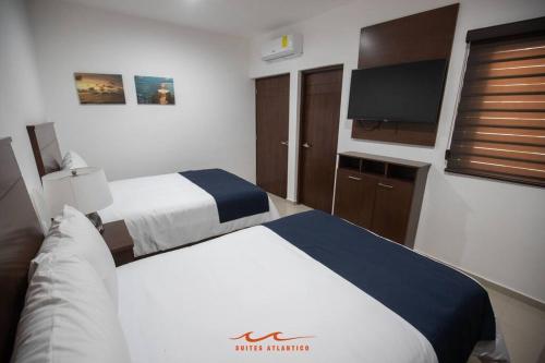 ein Hotelzimmer mit zwei Betten und einem Flachbildfernseher in der Unterkunft 1 Reserva hoy mismo y disfruta tu estancia in Mazatlán