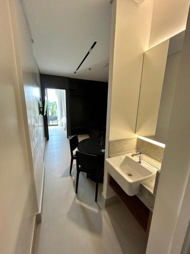 a bathroom with a sink and a table and a mirror at Porto Alto Resort - Porto de Galinhas in Porto De Galinhas