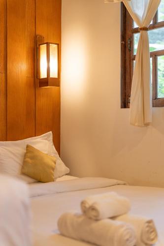 two beds in a room with towels on them at Monruamsuk Homestay Cafe and Bistro in Chiang Mai
