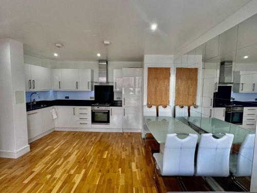 a kitchen with a glass table and white cabinets at Luxury 2 BED Entire Apartment-Near Tube & Shopping centre in Harrow