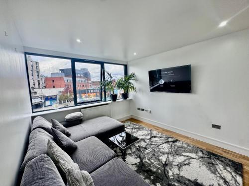 a living room with a couch and a flat screen tv at Luxury 2 BED Entire Apartment-Near Tube & Shopping centre in Harrow