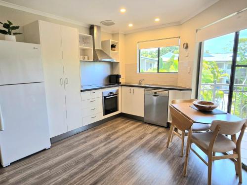 a kitchen with white cabinets and a table and chairs at Noosa River Retreat Holiday Apartments in Noosaville