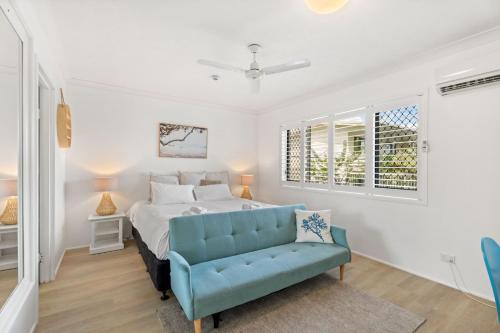 a bedroom with a bed and a blue couch at Charlton on The Esplanade in Hervey Bay