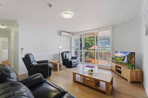 a living room with a couch and chairs and a tv at Charlton on The Esplanade in Hervey Bay