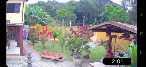 a garden with a bench and trees and a building at Pousada Refugio Prumirim in Ubatuba
