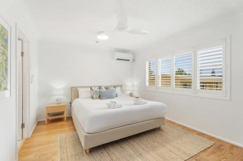 a white bedroom with a bed and a window at Charlton on The Esplanade in Hervey Bay