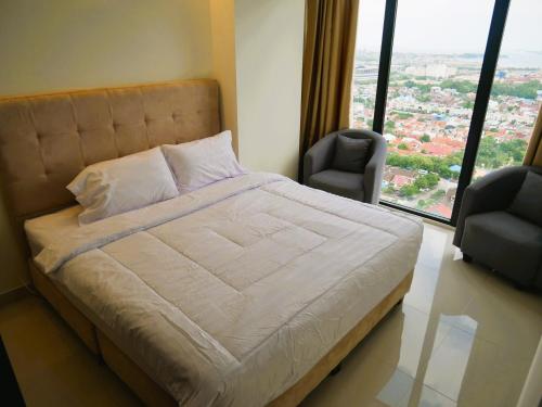 a bedroom with a large bed and two chairs at Meisterstadt Pollux Habibie in Batam Center