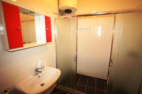 a bathroom with a shower and a sink and a mirror at Orange Studio Sea View in Sarandë