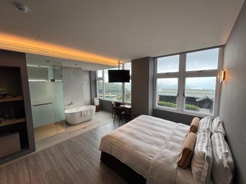 a bedroom with a bed and a tub and a window at Daybreak in Jiufen